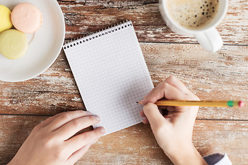 Image showing close up of hands, notebook, coffee and cookies