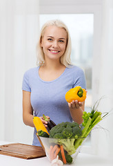 Image showing smiling young woman cooking vegetables at home