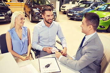 Image showing happy couple with car dealer in auto show or salon