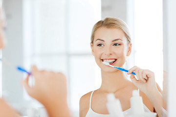 Image showing woman with toothbrush cleaning teeth at bathroom