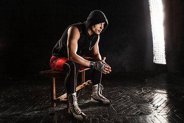 Image showing The muscular man sitting and resting on black