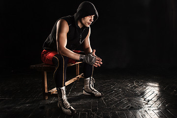 Image showing The muscular man sitting and resting on black