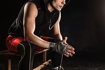 Image showing The muscular man sitting and resting on black