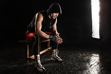 Image showing The muscular man sitting and resting on black