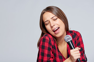 Image showing Emotional  girl singing a song in microphone