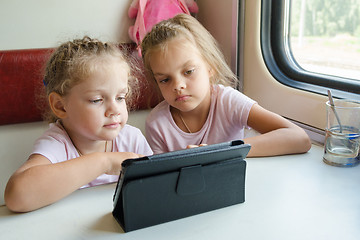 Image showing Two girls on a train watching a cartoon in the plate