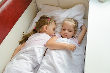 Image showing Sisters sleep on a cot in a train