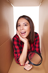 Image showing Girl opening a carton box and looking inside