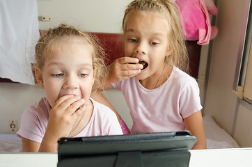 Image showing Sisters eating and looking at the tablet in the train