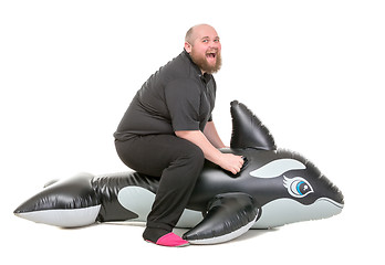 Image showing Fat Man Fun Jumping on an Inflatable Dolphin