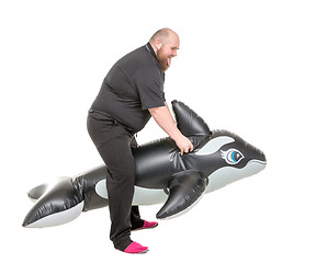 Image showing Fat Man Fun Jumping on an Inflatable Dolphin