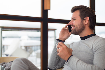 Image showing Informal businessman talking on phone by window.