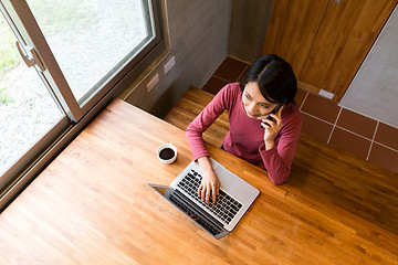 Image showing Top view of woman talk to cellphone and use of the notebook comp