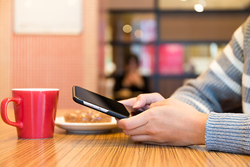 Image showing Woman texting message on cellphone at cafe