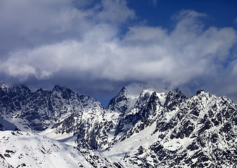 Image showing High snowy mountains in clouds at sunny day