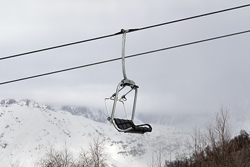 Image showing Chair lift and snowy mountains in haze