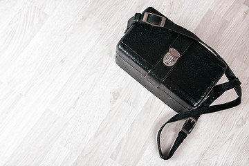 Image showing Vintage black leather case on a wooden floor