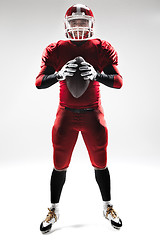 Image showing American football player posing with ball on white background