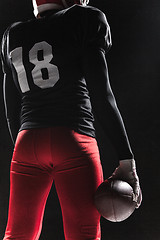 Image showing American football player posing with ball on black background