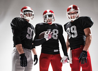 Image showing The three american football players posing with ball on white background