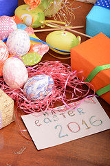 Image showing Easter with eggs in nest and yellow tulips over blue wooden table. Top view