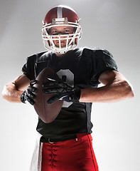 Image showing American football player posing with ball on white background