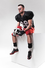 Image showing American football player sitting with  helmet on white background