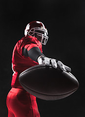 Image showing American football player posing with ball on black background