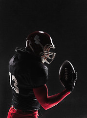 Image showing American football player posing with ball on black background