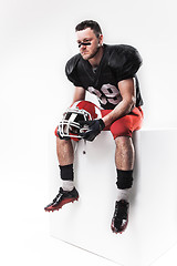 Image showing American football player sitting with  helmet on white background