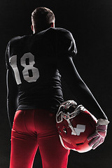 Image showing American football player posing with ball on black background