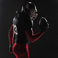 Image showing American football player posing with ball on black background