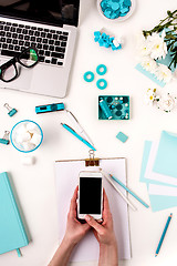 Image showing The female hands and smart phone against blue objects on white