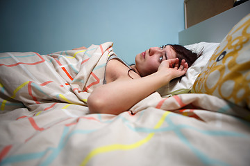 Image showing Side view of a sleepy young woman suffering from headache with eyes closed in bed at home