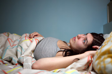 Image showing Young woman lying in bed suffering with insomnia  Noisy neighbour, stress, alarm sound, prevent from sleep concept