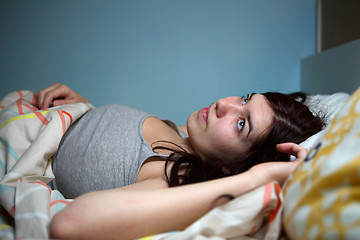 Image showing Young woman lying in bed suffering with insomnia  Noisy neighbour, stress, alarm sound, prevent from sleep concept