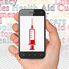 Image showing Medicine concept: Hand Holding Smartphone with Syringe on display