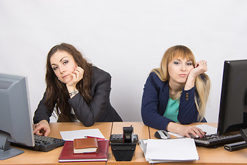 Image showing Two young employee of the office behind a desk looking sadly into the frame