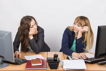 Image showing Two young office employee wearily looking at each other behind a desk