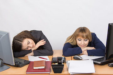 Image showing Two young office worker sleeping on desk for computers