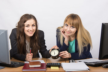 Image showing Two girls in the office with the clock happily await the end of the working day