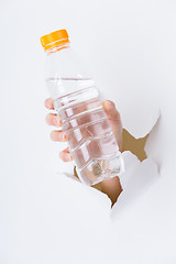 Image showing Hand through the hole in paper with plastic bottle