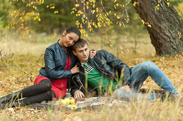 Image showing Young romantic couple sits on plaid. Autumn picnic