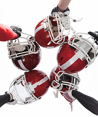 Image showing The hands of american football players with helmets on white background