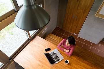 Image showing Top view of woman look out of the window after using laptop comp