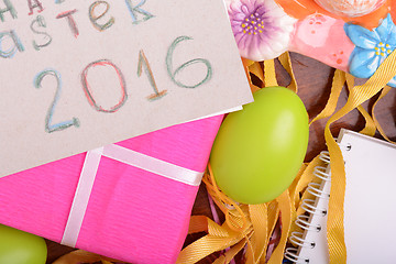 Image showing Easter background with colorful eggs and yellow tulips over white wood. Top view with copy space