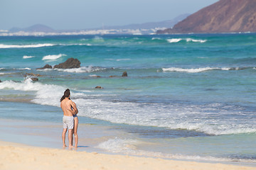 Image showing Young couple embracing on sandy beach.