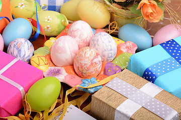 Image showing Easter background with colorful eggs and yellow tulips over white wood. Top view with copy space