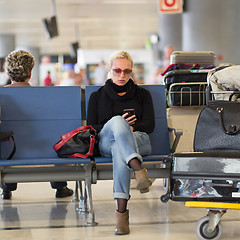 Image showing Female traveler using cell phone while waiting on airport.