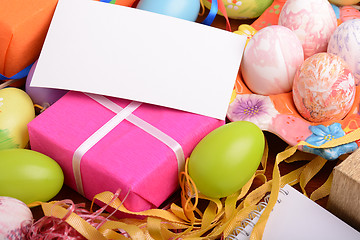 Image showing Easter background with colorful eggs and yellow tulips over white wood. Top view with copy space